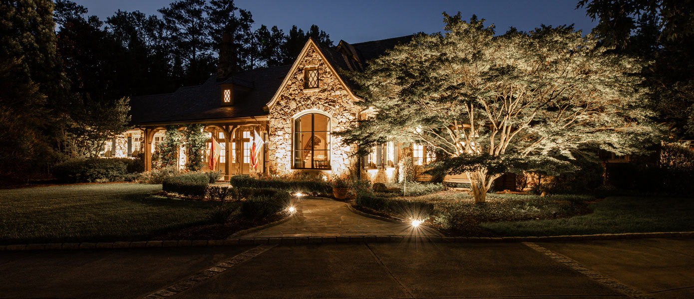 A house with trees and lights at nightDescription automatically generated